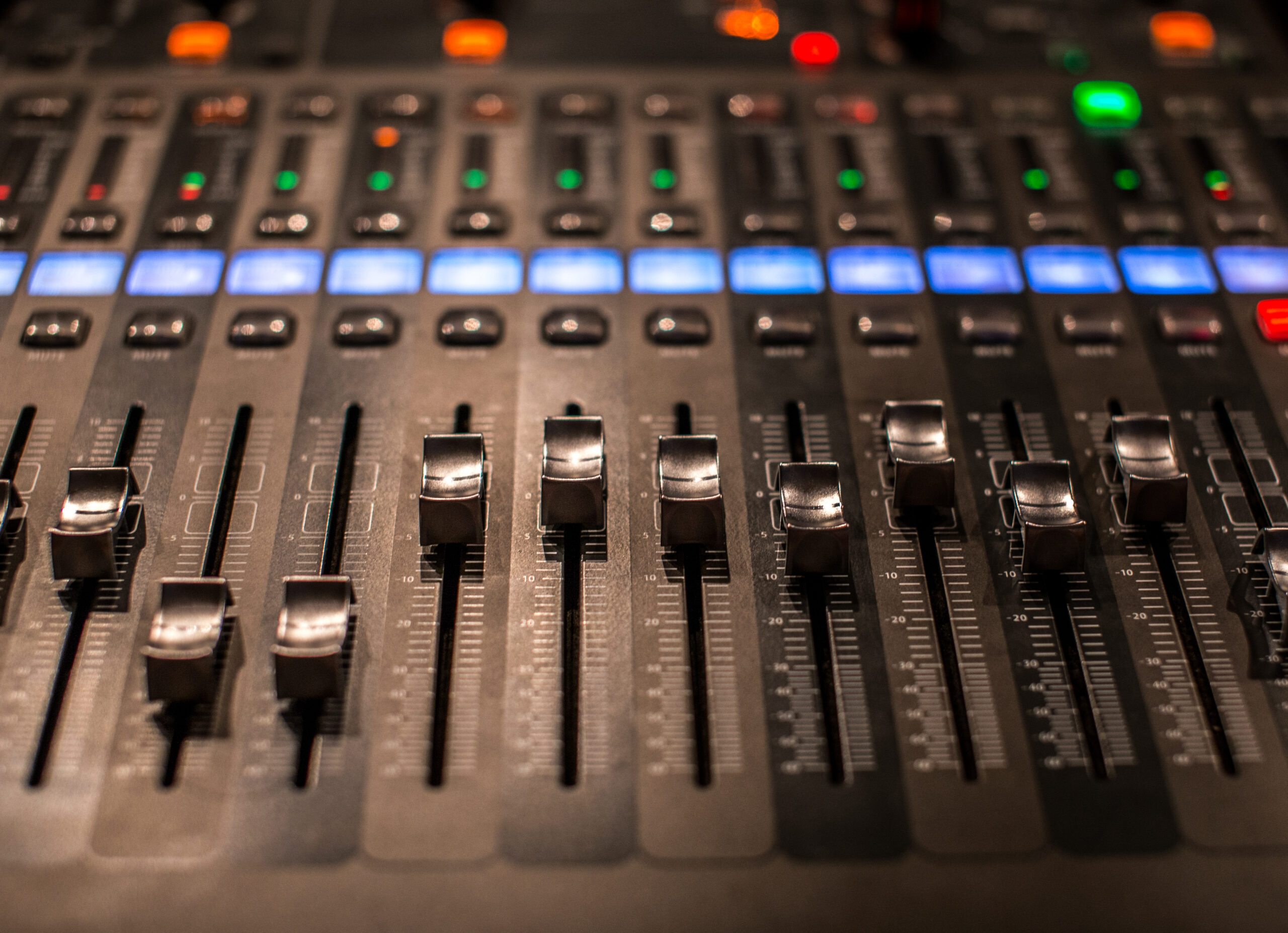 Close-up of digital mixing console faders and volume meters during an audio engineering session at YMVRSL in Ankara.