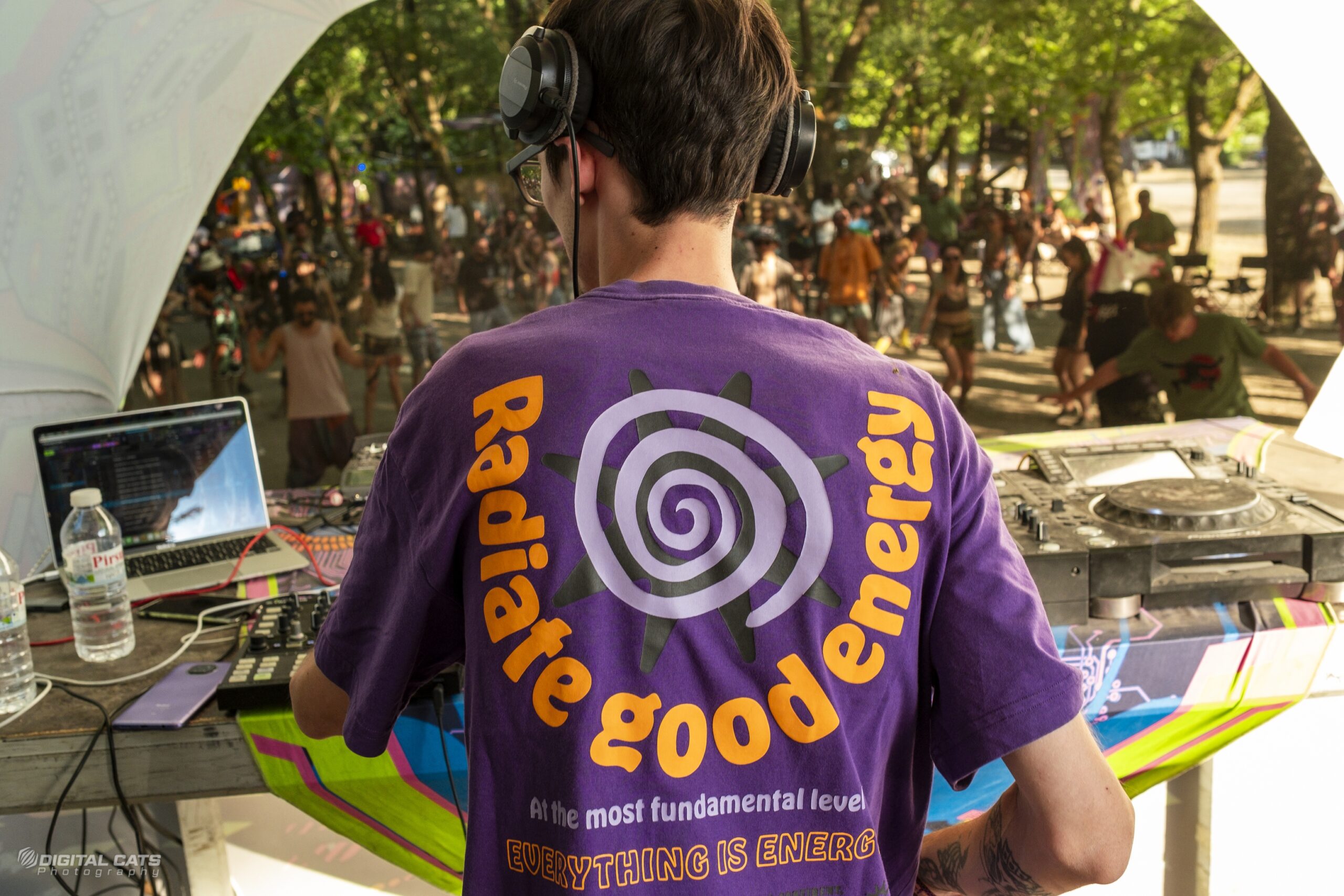 İzmir'de bir underground etkinlikte 'radiate good energy' tişörtlü DJ ve gün batımı ışığında yakalanmış otantik atmosfer.